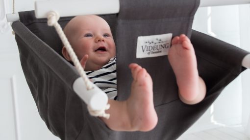 Grå babygunga Oden från Videung of Sweden i ljusgrått. Glad baby som gungar den.